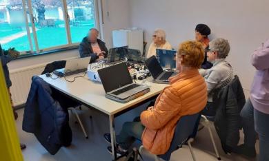 Des adultes sont assis à une table avec des ordinateurs.