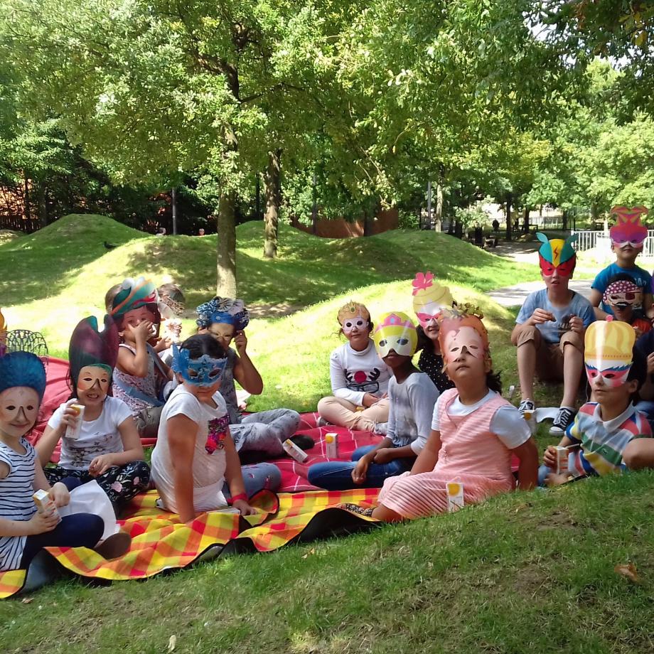 De nombreux enfants masqués regardent l'appareil photo, assis dans la nature