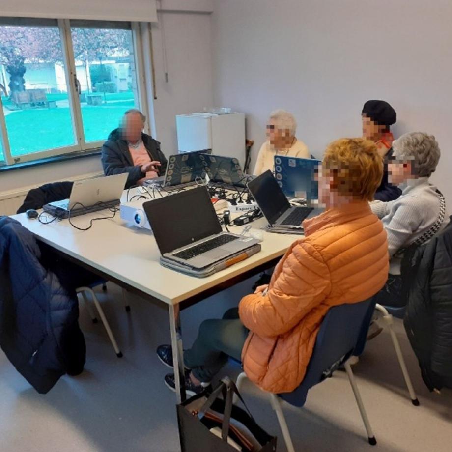 Des adultes sont assis à une table avec des ordinateurs.